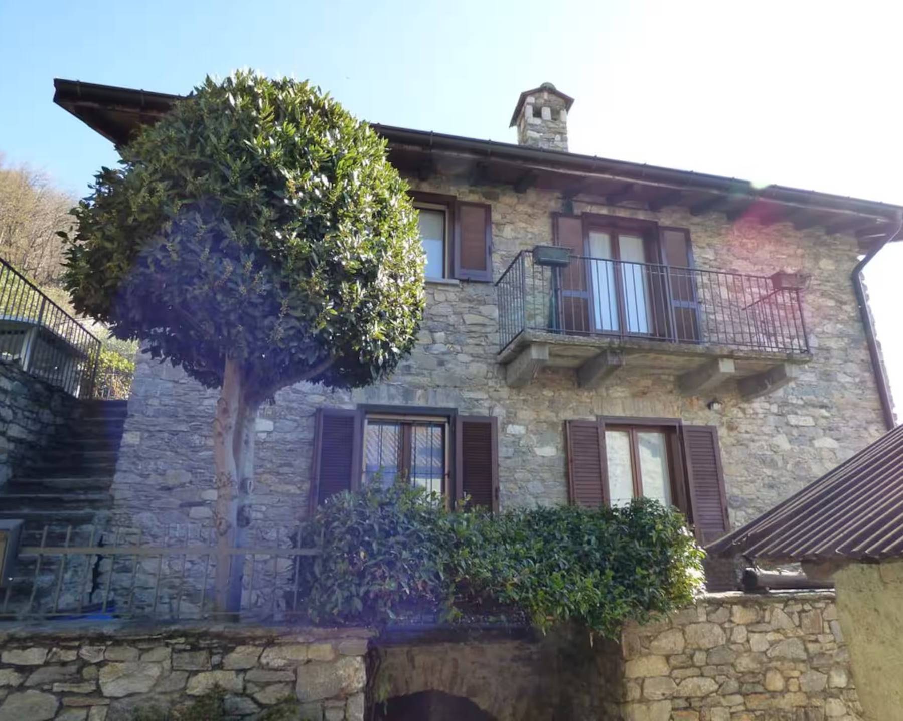Villa Oppilia, restaurert steinhus med brune treskodder og smijernsbalkong i Montemezzo