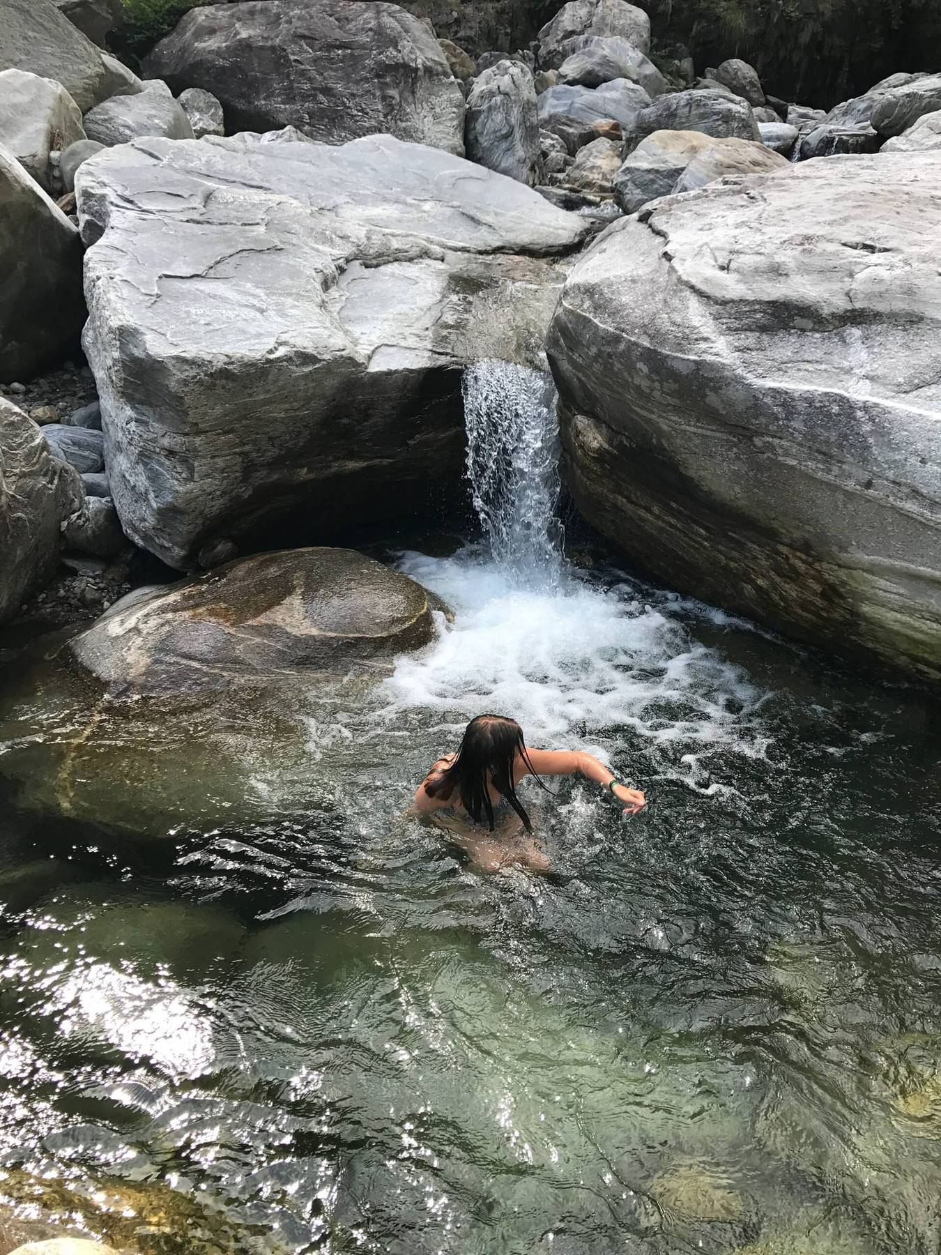 Bad i en klar elvekulp under en foss en varm sommerdag