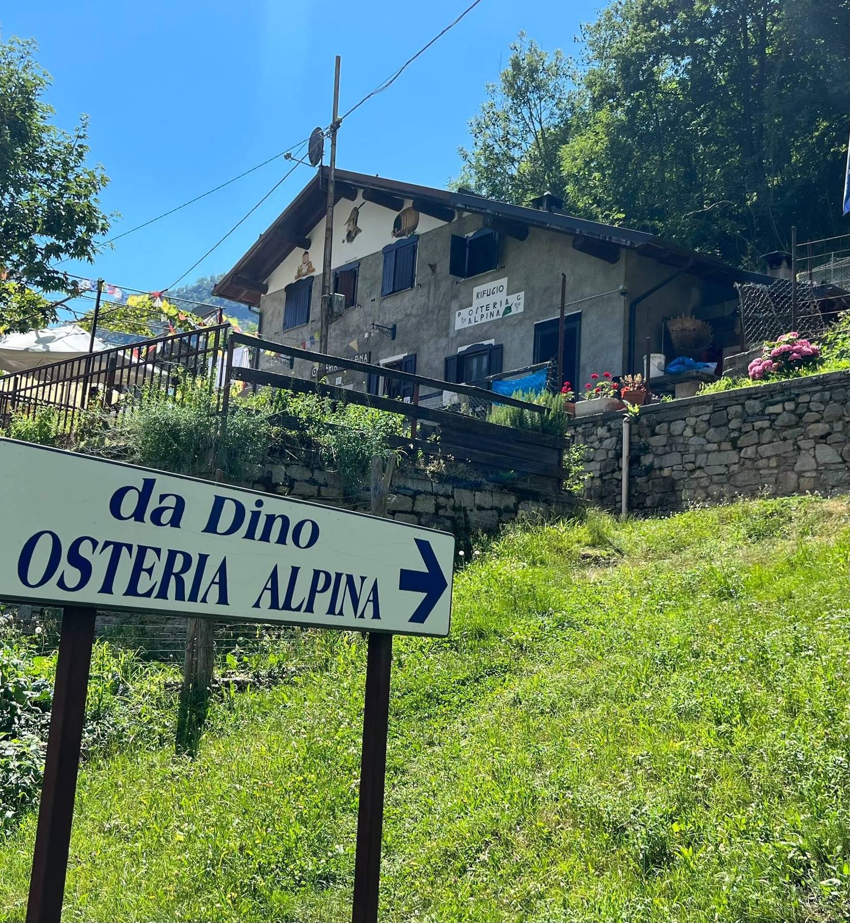 Skilt til Osteria Alpina da Dino ved en fjellsti